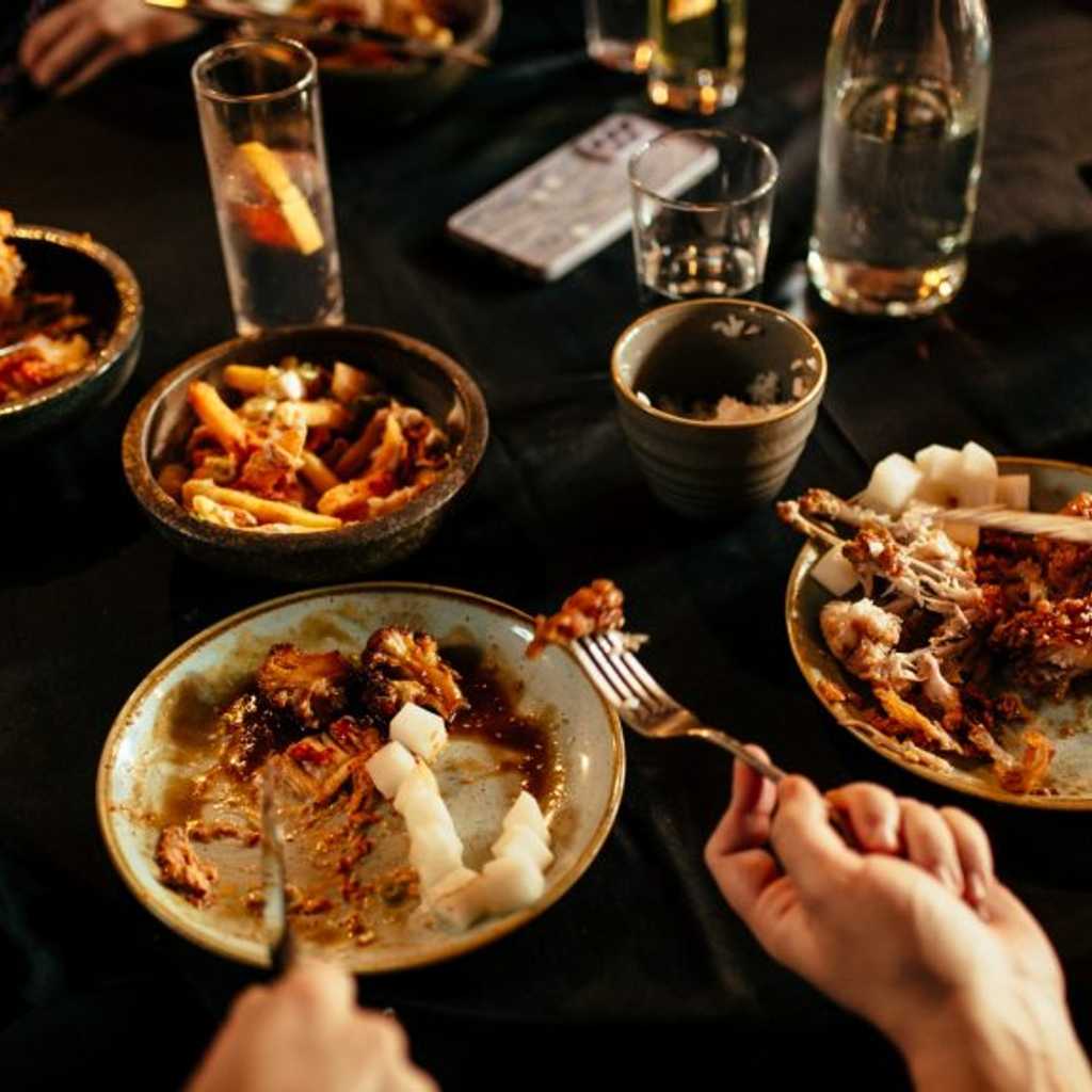 People eating at table with many plates of food